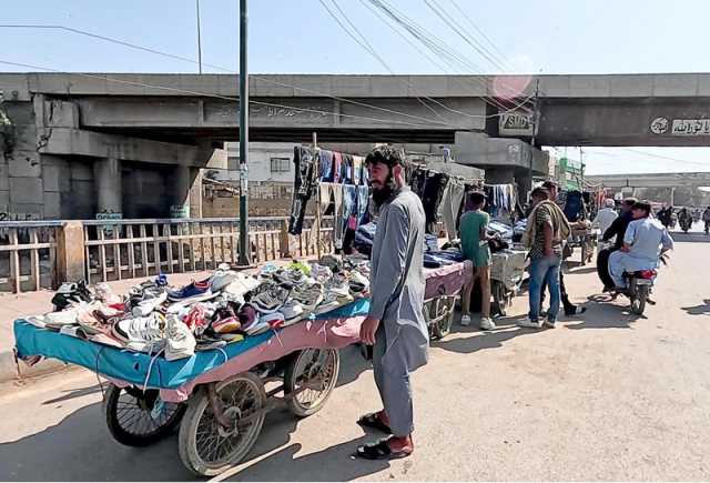 تین ہٹی پل پر مزدور ریڑھی پر جوتے اور کپڑے فروخت کررہے ہیں