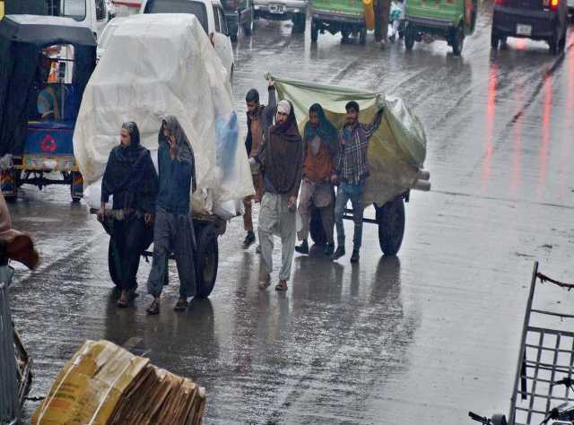 راولپنڈی، موسم سرما کی بارش کے دوران راہگیر اپنی منزل کی جانب رواں دواں ہیں